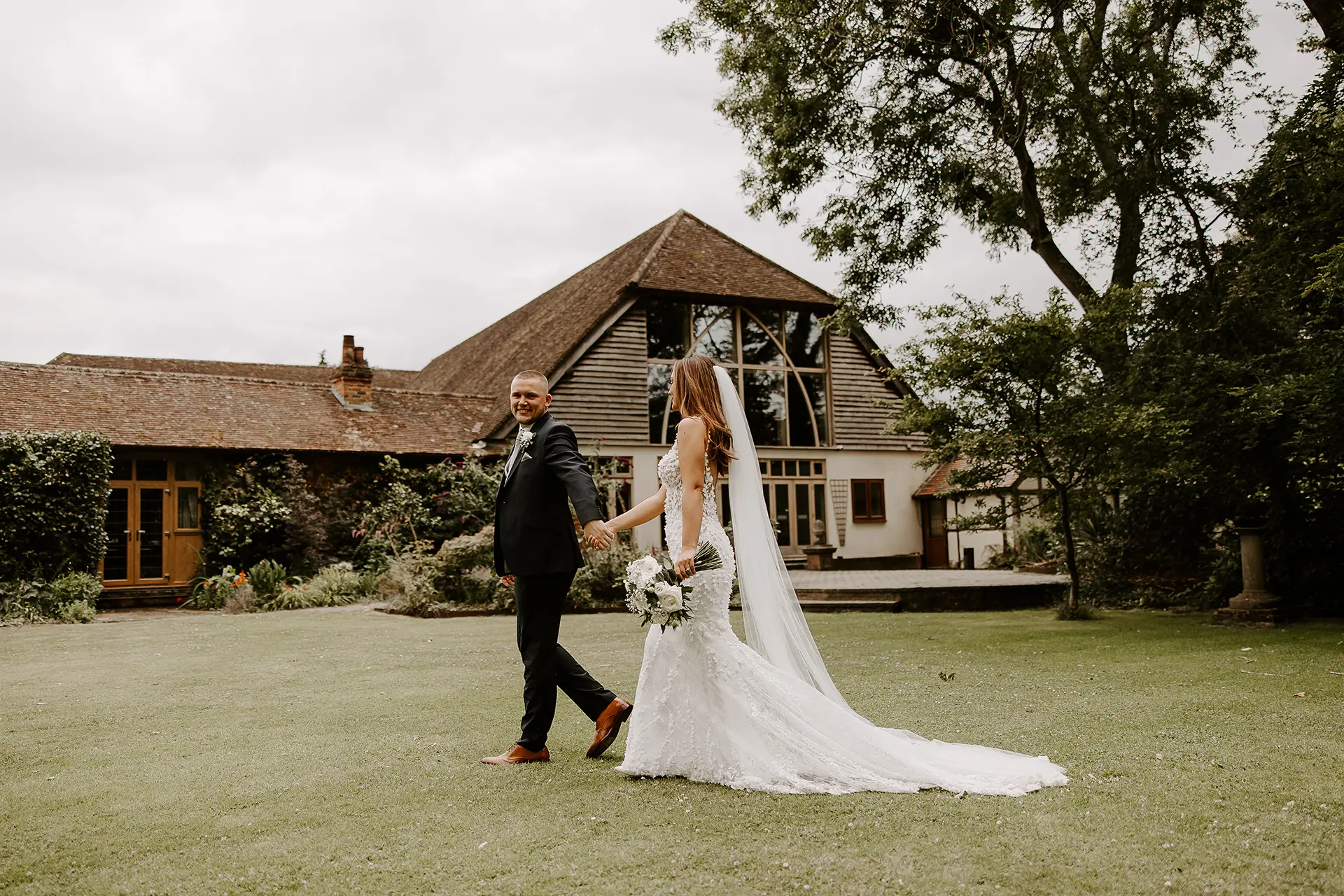 Bride and groom walking through the gardens at Rivervale Barn