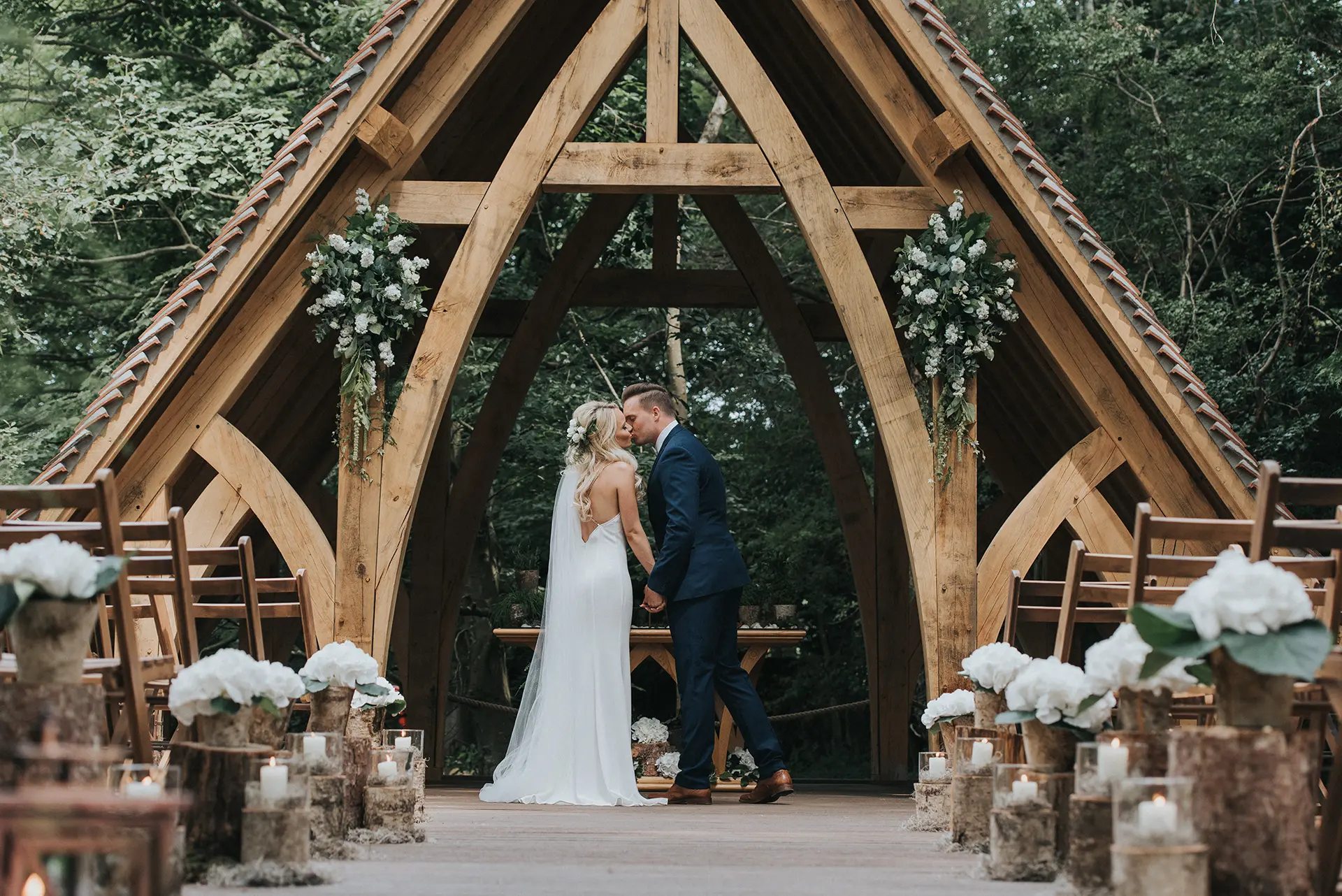 Bride and groom kissing under the Spinney at Rivervale Barn