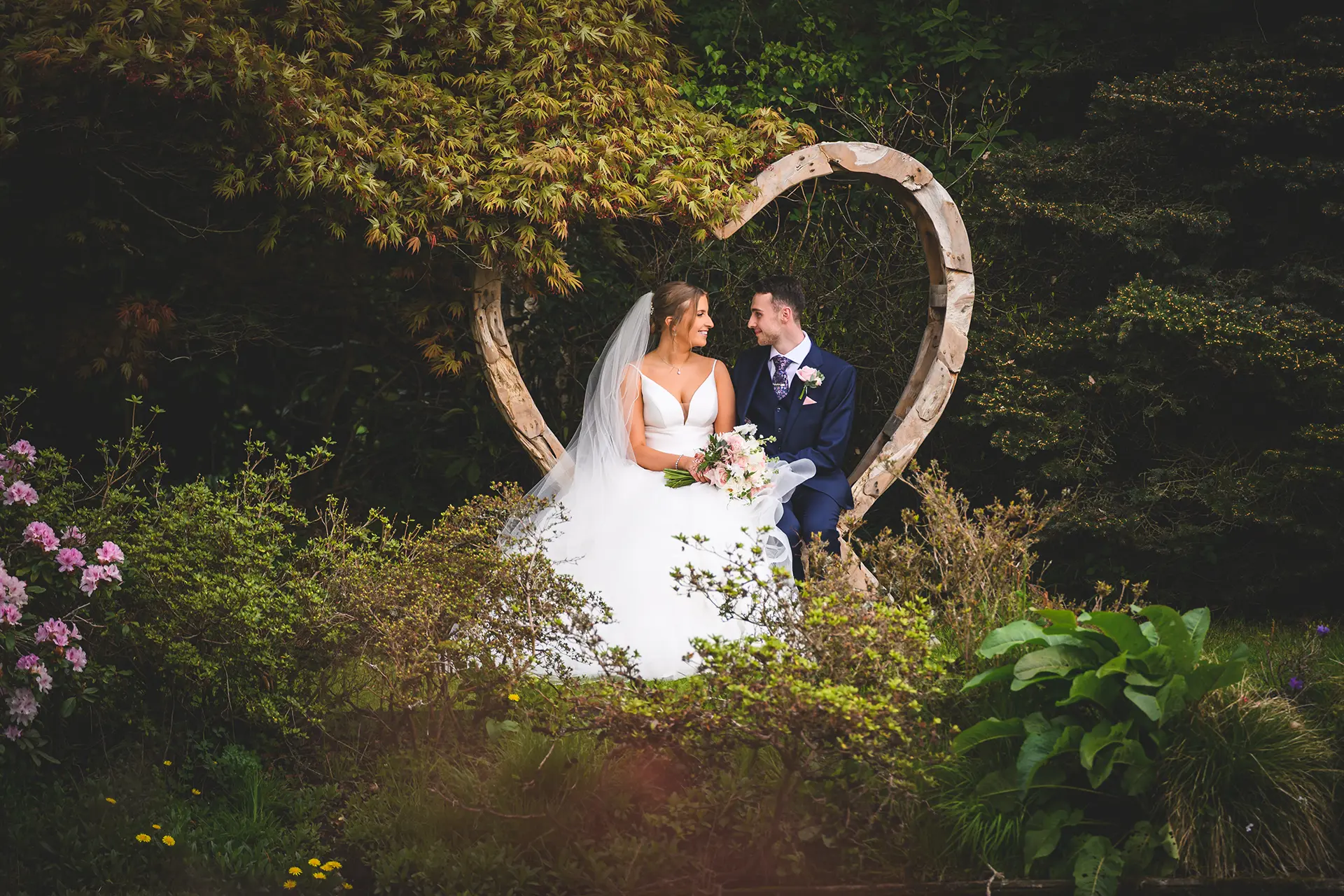 Couple sat on the heart-shaped bench in Rivervale Barn's gardens