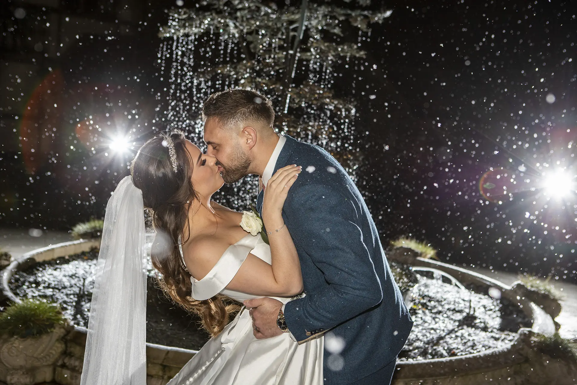 Couple kissing by the fountain in the courtyard at Rivervale Barn
