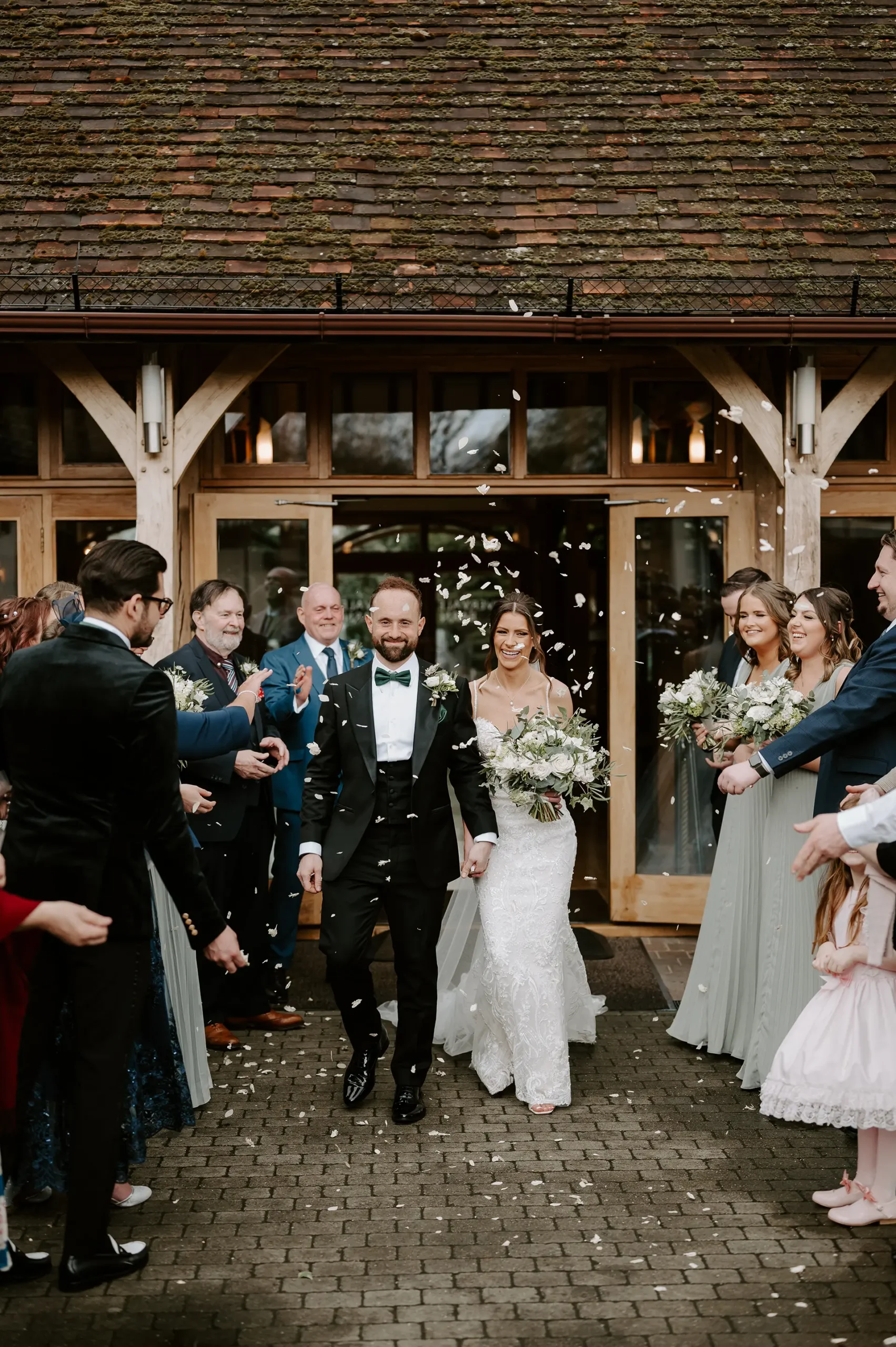 Wedding guests throwing confetti at bride and groom just married at Rivervale Barn