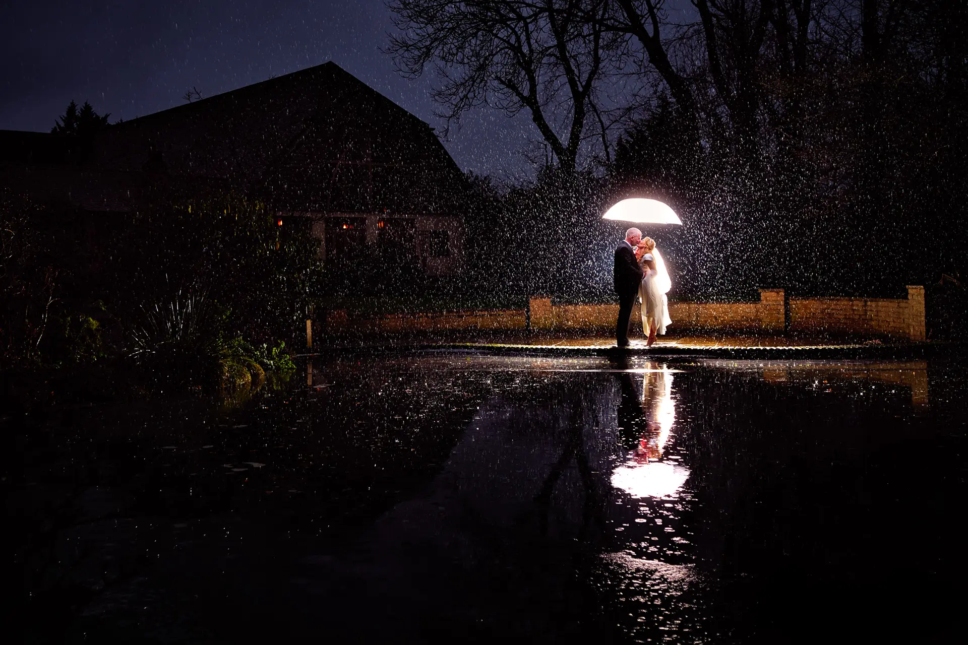 Bride and groom under an umbrella in the rain at Rivervale barn