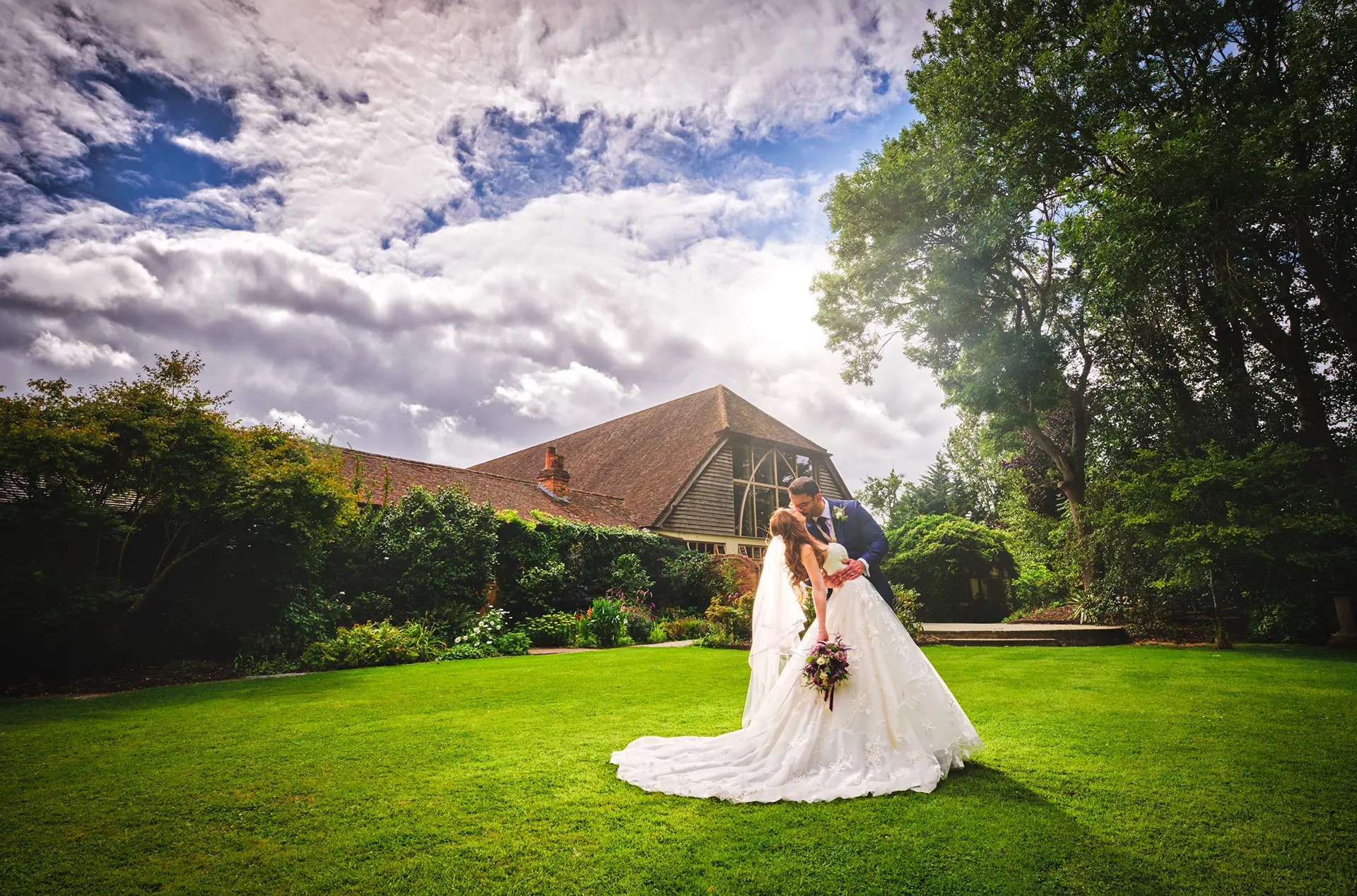 Bride and groom kissing in Rivervale Barn's gardens