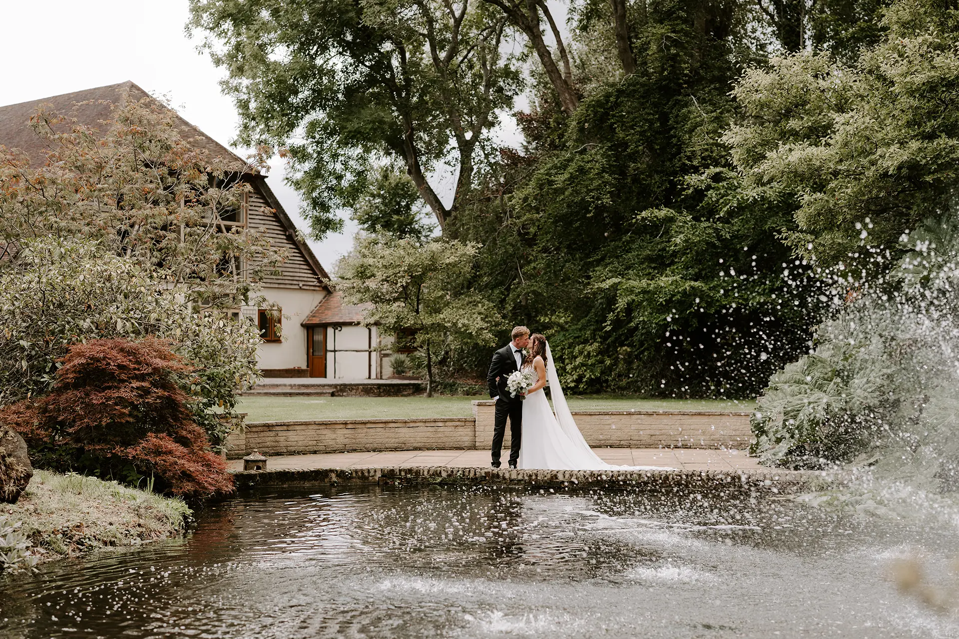 Couple kissing by the fountain in Rivervale Barn's gardens
