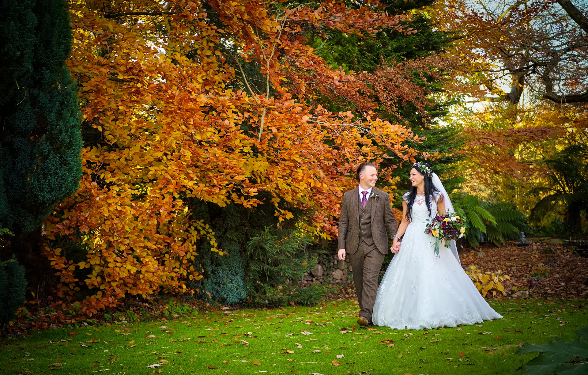 Bride and groom walking through Rivervale Barn's gardens in autumn