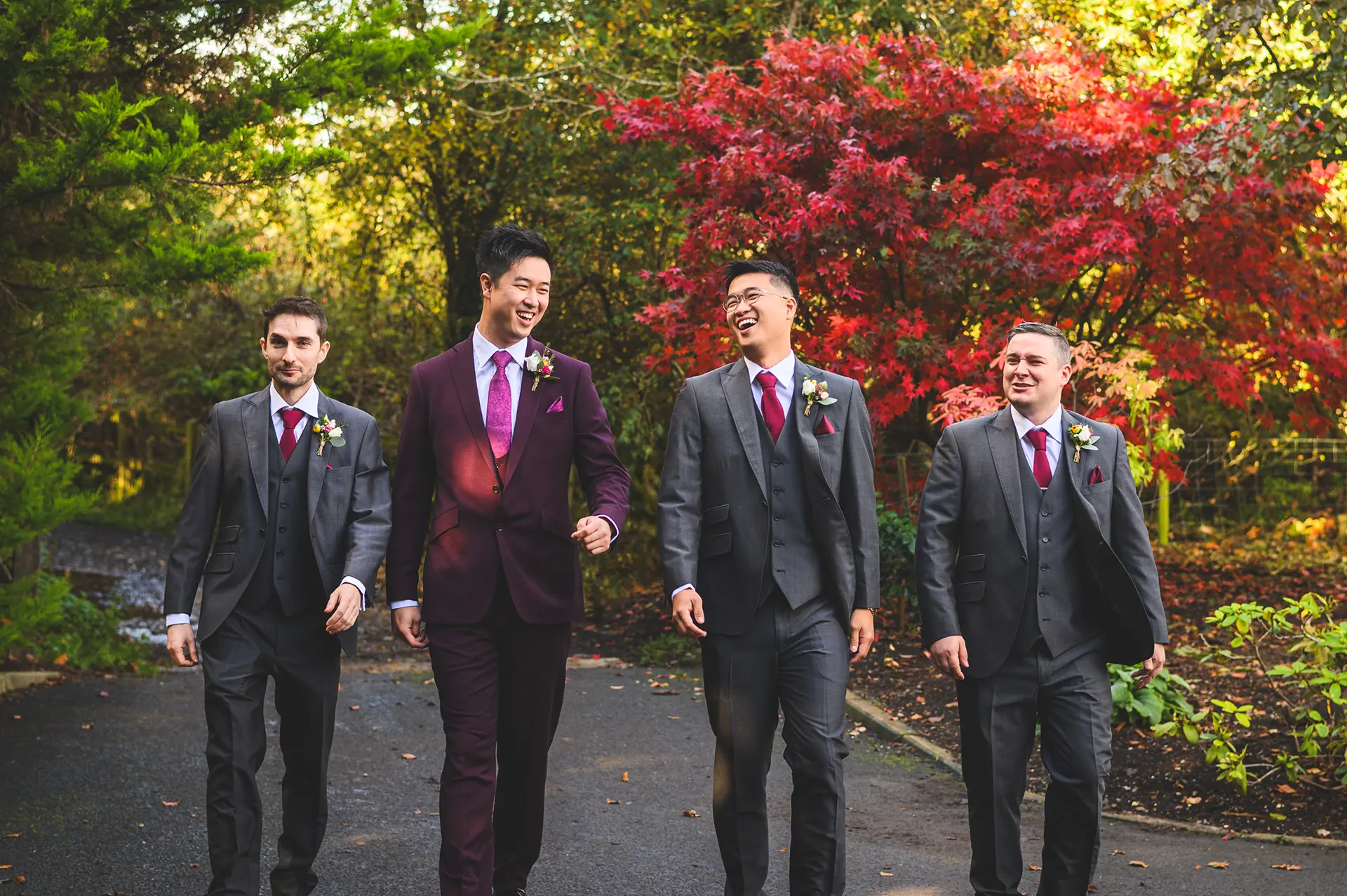 Groom and groomsmen walking through gardens in autumn at Rivervale Barn